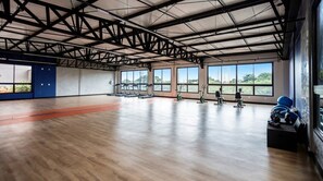 Une salle de sport spacieuse, dotée d’un haut plafond, de grandes fenêtres et de divers appareils d’exercice.