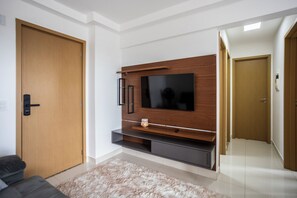 Un salón moderno con un televisor de pantalla plana montado en una pared de madera, un sofá oscuro y una alfombra mullida.