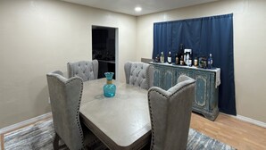 A dining area with a table and four chairs, a bar with bottles, and a kitchen in the background. - Affordable private room King bed in Thonotosassa, shared space (Thonotosassa)