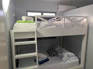 A bunk bed room with a window, a white shelf, and a blue item on the lower bunk. - Private Villa Minutes from the Beach in Beautiful Boquerón — Cool A/C Included (Boquerón)