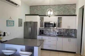 Een moderne keuken met een centraal eiland, roestvrijstalen apparatuur en een reliëf backsplash.