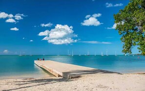 A beach with a concrete pier extending into calm turquoise waters, surrounded by clear skies and sparse clouds. - Private Villa Minutes from the Beach in Beautiful Boquerón — Cool A/C Included (Boquerón)