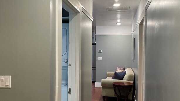 A hallway with a wooden floor, a light blue door, and a beige sofa with a small table. - Charming 3-bedroom apartment near Piedmnot and Oakland with AC for your stay (Oakland)