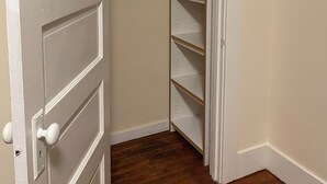 A closed door with a white handle, a wooden floor, and a white wall. - Charming 3-bedroom apartment near Piedmnot and Oakland with AC for your stay (Oakland)