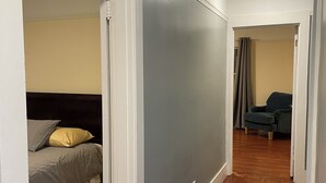 A bedroom with a bed, a grey sliding door, and a wooden floor. - Charming 3-bedroom apartment near Piedmnot and Oakland with AC for your stay (Oakland)