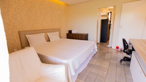 A hotel room with a large bed, a desk, and a chair. - Casa c/ Piscina a 550m da Praia | Até 10 hóspedes (Lauro de Freitas)