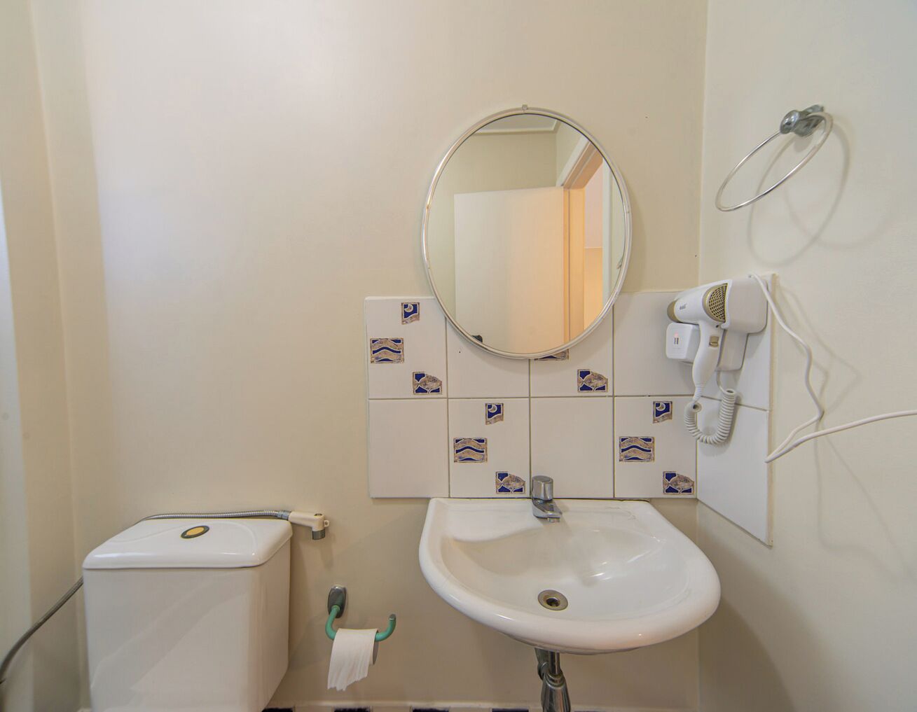 Une salle de bain avec des toilettes, un lavabo et un miroir.