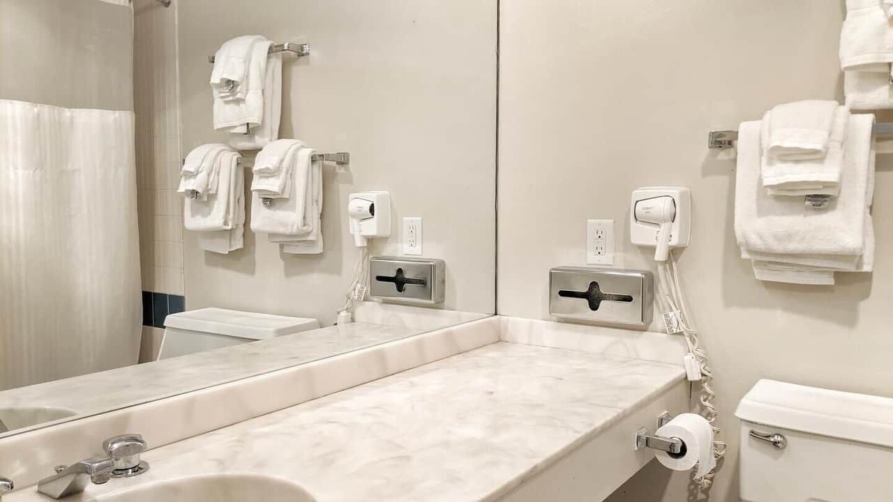 Une salle de bain équipée d’un grand miroir, d’un lavabo, de toilettes et de distributeurs de serviettes.