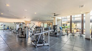 Ett gym med olika träningsmaskiner, stora fönster och ett klinkergolv.
