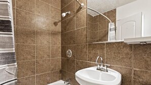 A bathroom with a bathtub, a sink, and a shower. - Temple View Inn Ogden (Ogden)