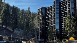A modern building with a grid-like facade, surrounded by a forested area.