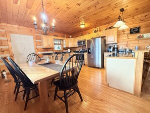 Ein Holzblockhaus-Interieur mit Essbereich, Küche und einer kleinen Kücheninsel.