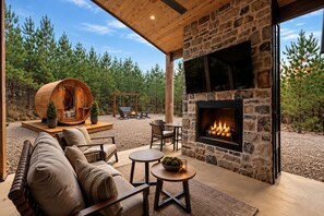 A cozy outdoor living area with a stone fireplace, seating, and a wooden barrel structure. - Hot Tub,  Barrel Sauna, Couples Retreat Broken Bow (Broken Bow)
