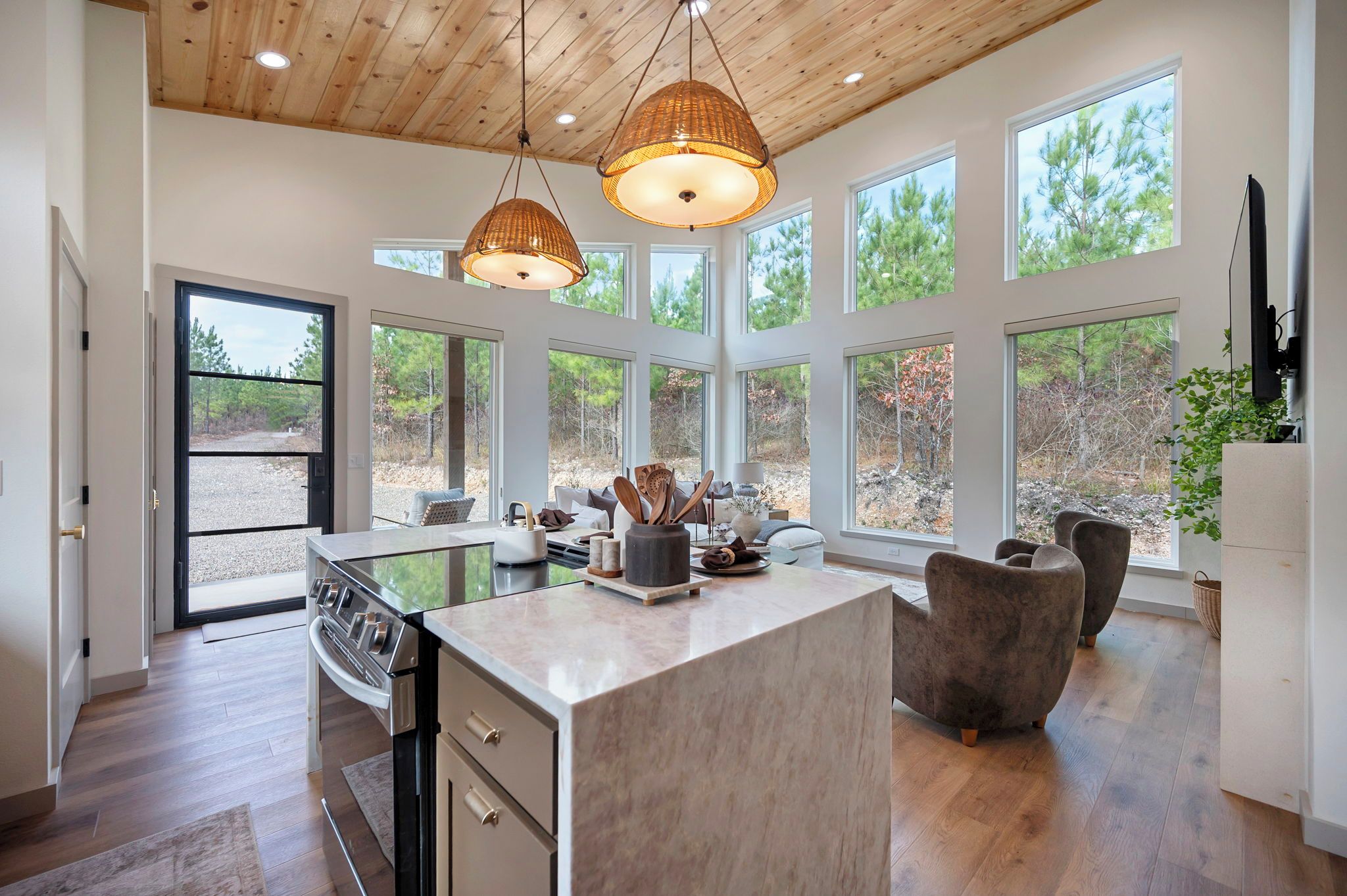 Una cucina moderna con isola centrale, ampie finestre e soffitto in legno.