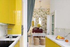 A kitchen with yellow cabinets, a white countertop, and a mirror above the sink. - Waou Anibal Heritage Sevilla Centro (Sevilla)
