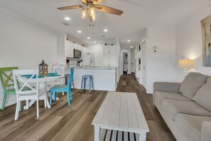 A modern kitchen with white cabinets, a central island, and a ceiling fan. - Beachside Gem ~ Remodeled Luxury Steps to Sand (Miramar Beach)