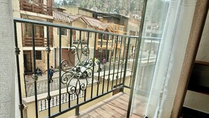 Ein Balkon mit Metallgeländer, Blick auf eine Straße mit Gebäuden und ein Fliesenboden.