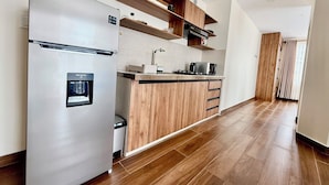 Eine moderne Küche mit einem Edelstahlkühlschrank, Holzschränken und einer eingebauten Mikrowelle.