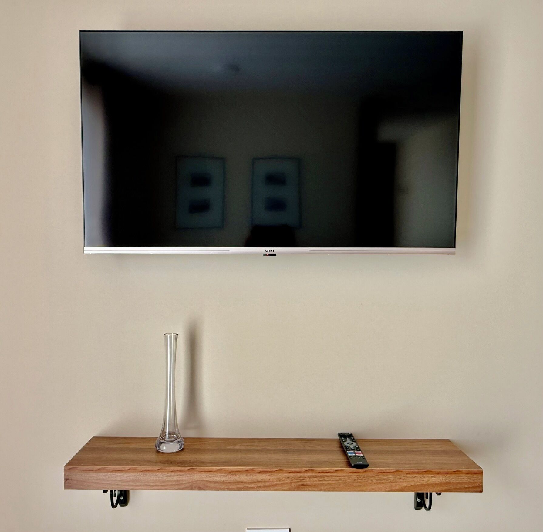 Un televisor de pantalla plana montado en la pared sobre una repisa de madera.