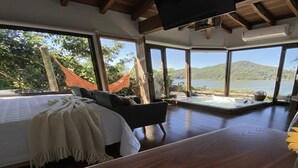 A bedroom with a bed, a sofa, and a hot tub. - HOSPEDARIA PONTA DA PITEIRA (Imbituba)