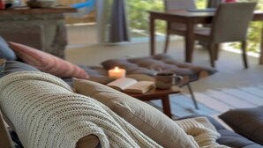A cozy living room with a sofa, a table with a candle, and a view of the outdoors. - HOSPEDARIA PONTA DA PITEIRA (Imbituba)