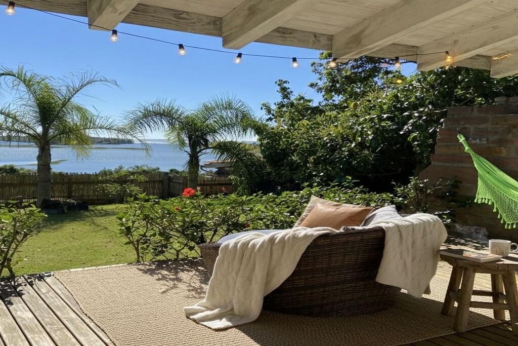 A covered outdoor seating area with a wicker sofa, a table, and a hammock.