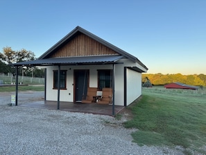 Eenlaags gebouw met een veranda, een schommel en een kleine tafel.