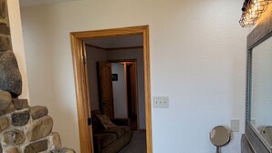 Un baño con pared de piedra, tocador de madera, lavamanos y espejo.