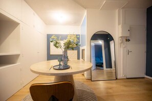 A dining area with a round table, a vase with flowers, and a mirror on the wall. - L'Ecrin Bleu - Spacious - Ideal for couples & professionals - WiFi - Station & Hyper center (Angoulême)