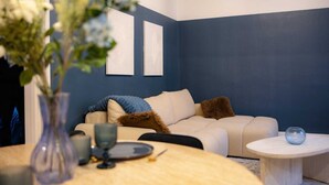 A living room with a beige sofa, a round table with a vase and plates, and a blue accent wall. - L'Ecrin Bleu - Spacious - Ideal for couples & professionals - WiFi - Station & Hyper center (Angoulême)
