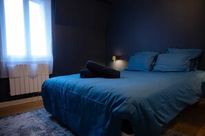 A bedroom with a bed, a nightstand, a lamp, and a window with curtains. - L'Ecrin Bleu - Spacious - Ideal for couples & professionals - WiFi - Station & Hyper center (Angoulême)