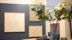 A dining area with a round table, three framed wall art pieces, and a vase with flowers. - L'Ecrin Bleu - Spacious - Ideal for couples & professionals - WiFi - Station & Hyper center (Angoulême)