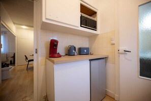 A compact kitchen with a built-in microwave, a coffee maker, and a toaster on the countertop. - L'Ecrin Bleu - Spacious - Ideal for couples & professionals - WiFi - Station & Hyper center (Angoulême)