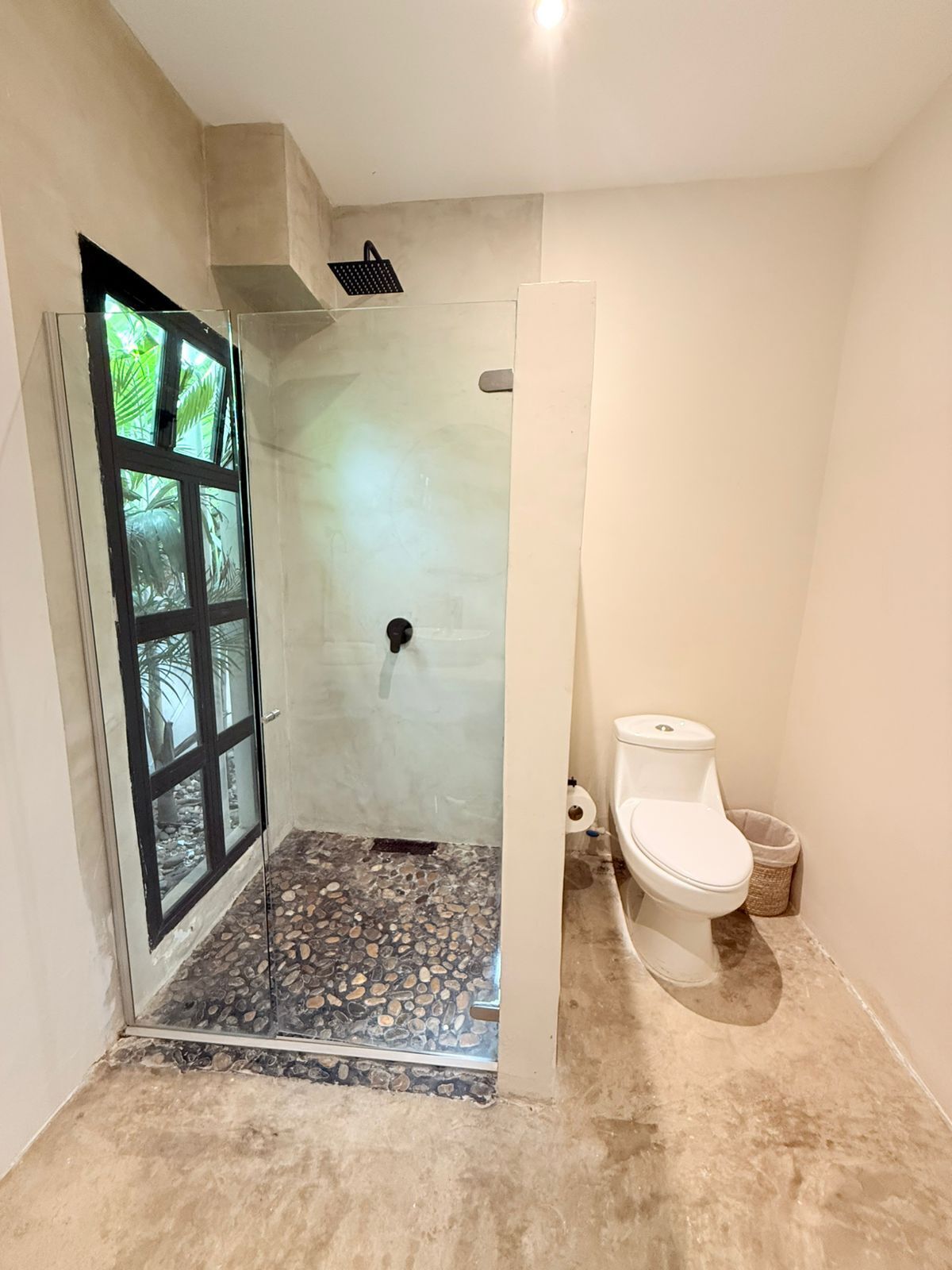 Ein Badezimmer mit Duschkabine, Toilette und Boden in Kieselsteindekor.