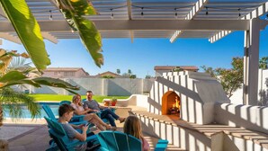 A patio area with a fire pit, seating, and a pool. - Pool & Spa • Outdoor Fireplace • BBQ • Pool Table (Goodyear)