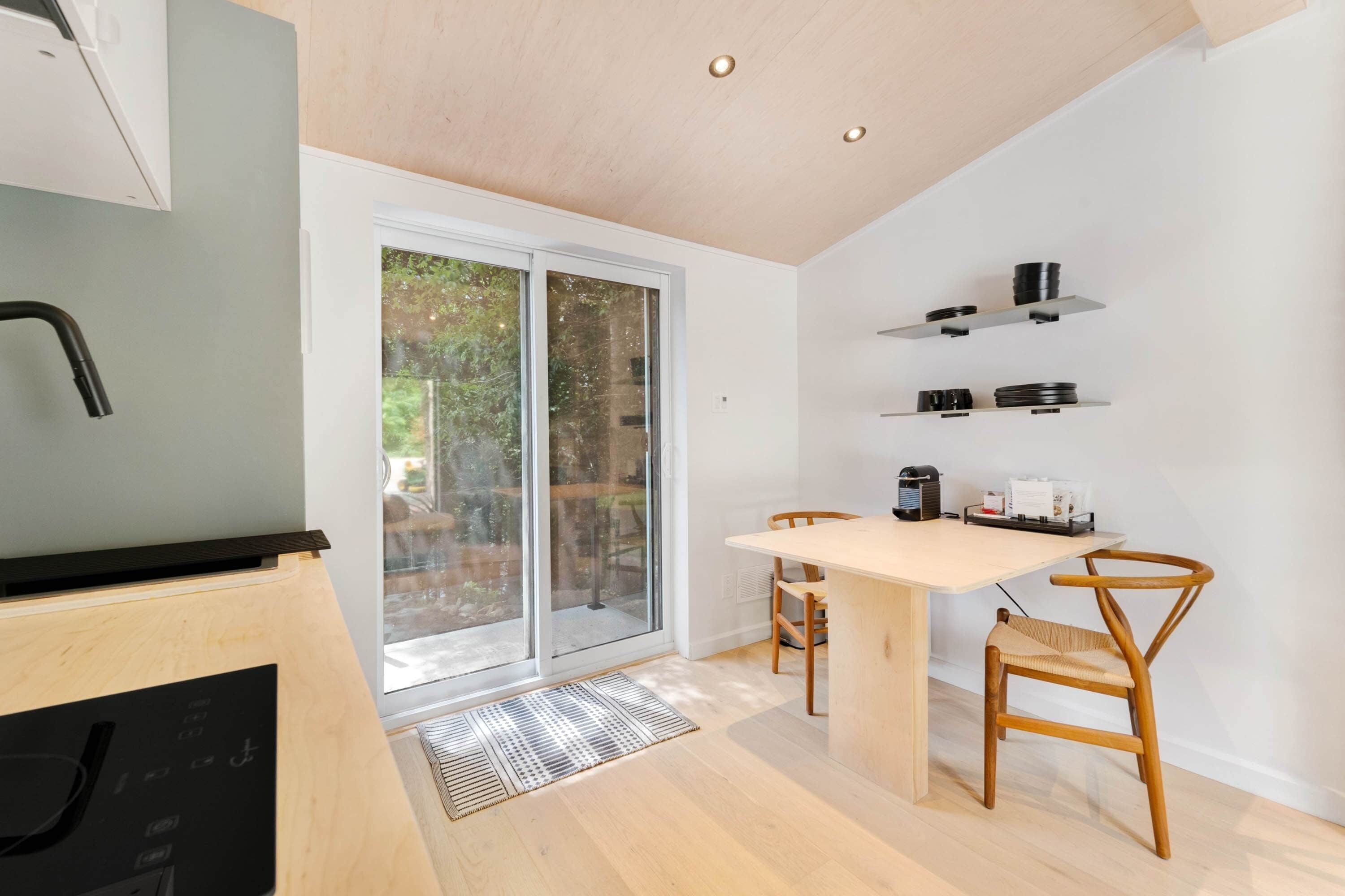 Une cuisine moderne équipée d’un lave-vaisselle intégré, d’une table à manger avec des chaises et d’une porte-fenêtre coulissante donnant sur un balcon.