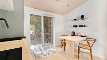 Une cuisine moderne équipée d’un lave-vaisselle intégré, d’une table à manger avec des chaises et d’une porte-fenêtre coulissante donnant sur un balcon.