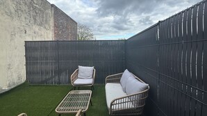 A small outdoor patio with artificial grass, wicker furniture, and a black fence. - House 8 pers - Jacuzzi - Near Lille & Belgium (Tourcoing)