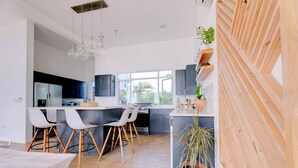Een moderne keuken met een groot eiland, barstoelen en een houten accentmuur.