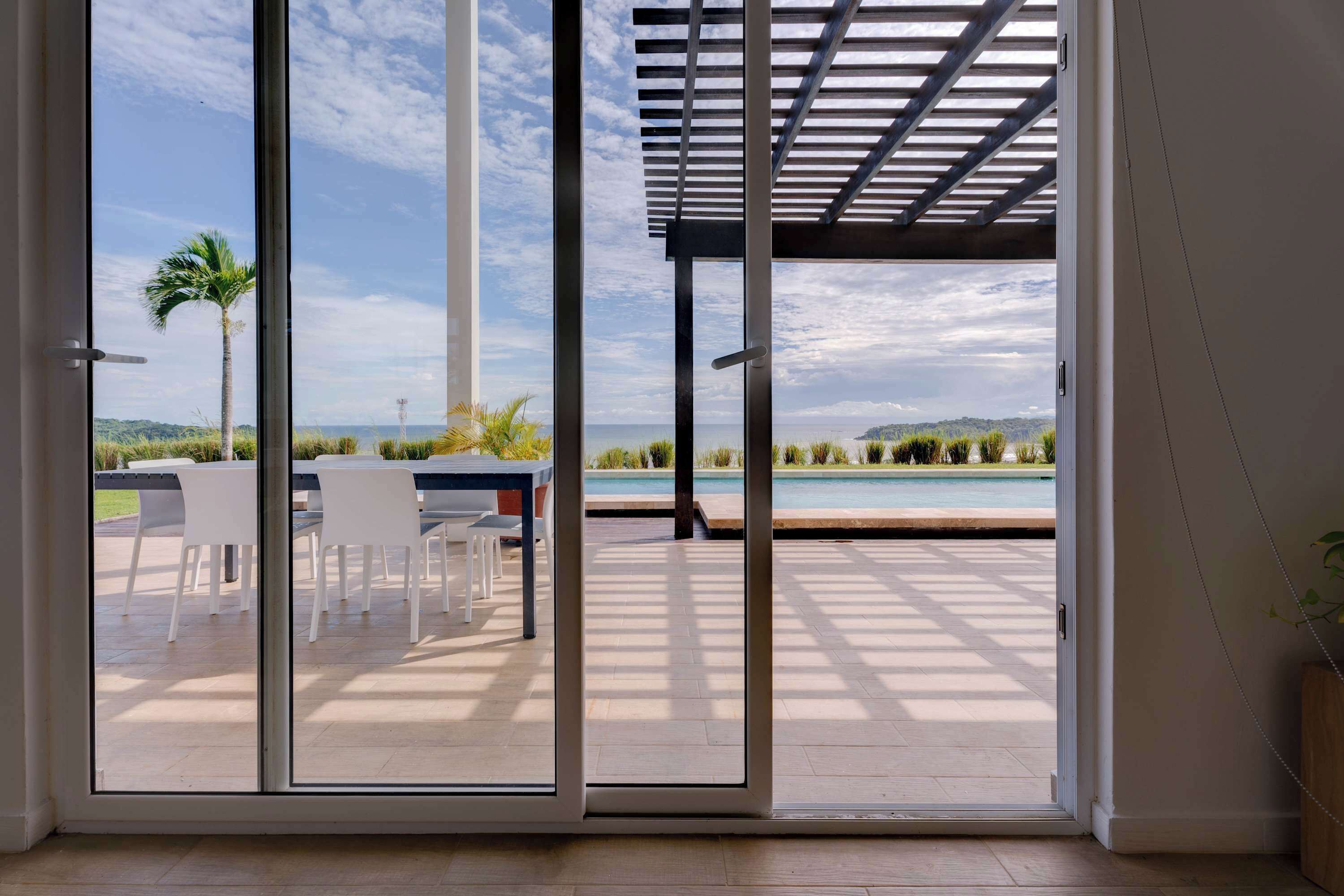 A modern room with a sliding glass door leading to an outdoor patio with a pool and chairs.
