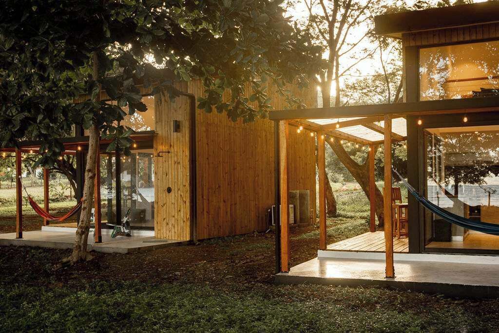 Una baita di legno con una porta in vetro, un'amaca e una terrazza.