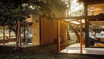 Una baita di legno con una porta in vetro, un'amaca e una terrazza.