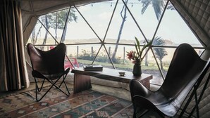 Ein Zeltraum mit zwei Ledersesseln, einem kleinen Tisch und Blick ins Freie.