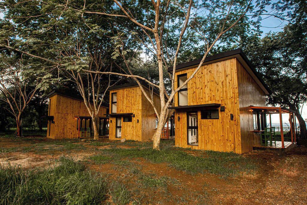 A wooden cabin complex with multiple rooms, surrounded by trees.