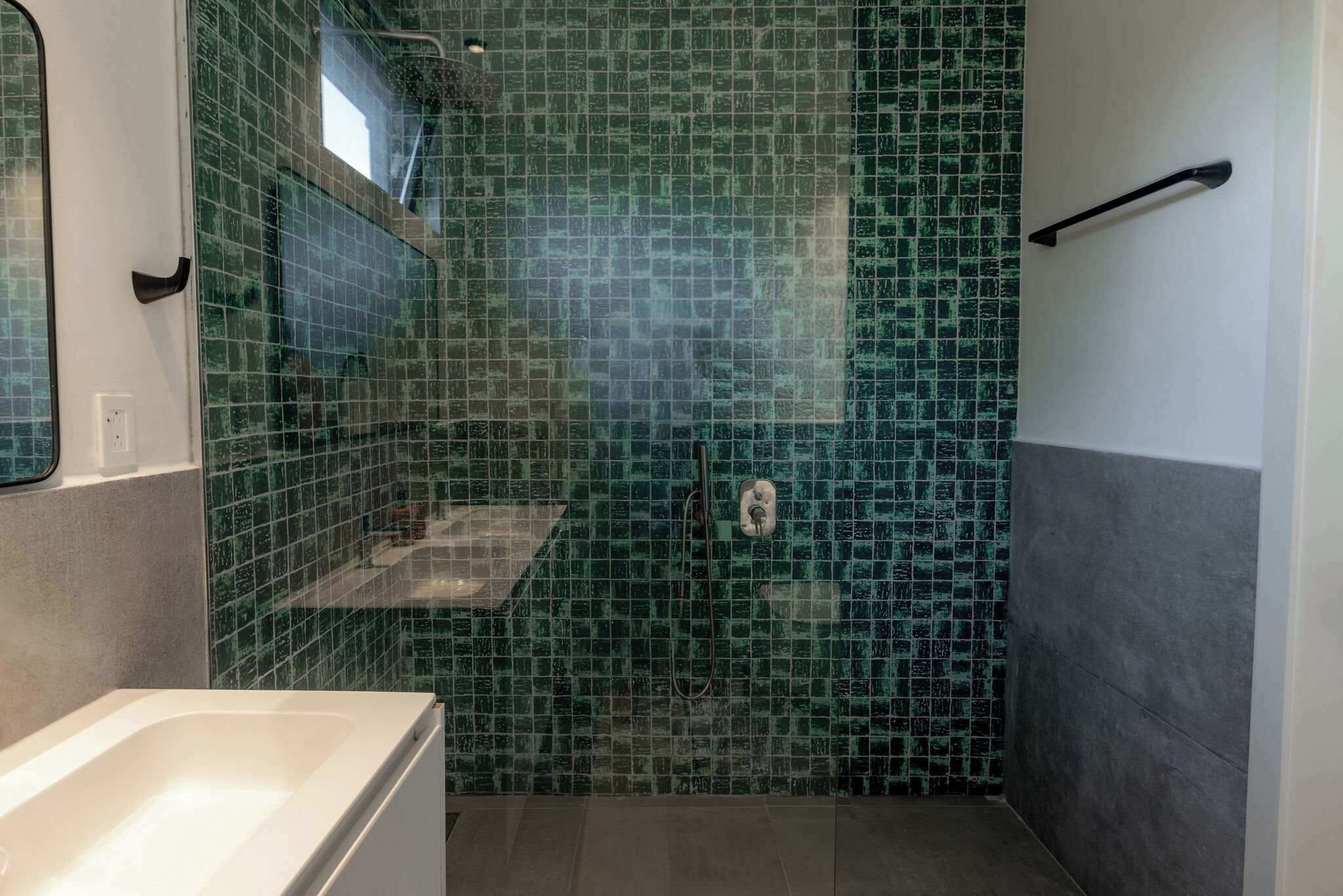 Un bany amb zona de dutxa, un lavabo i una banyera.