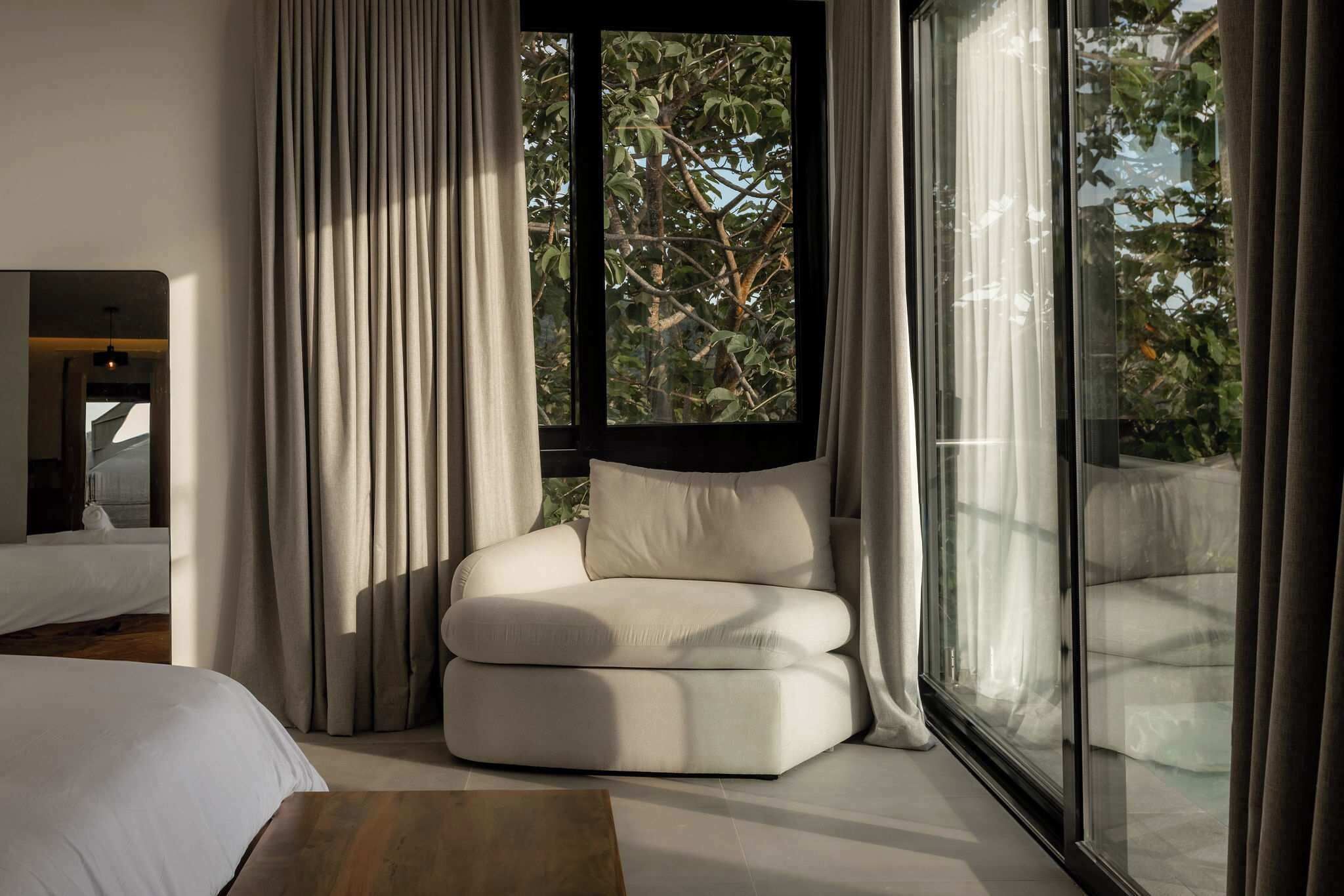 Un dormitorio moderno con un ventanal grande, un sofá blanco y una cama.