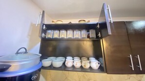 Une cuisine équipée d’une machine à café intégrée, d’une casserole, ainsi que de plusieurs tasses et de bocaux posés sur le plan de travail.