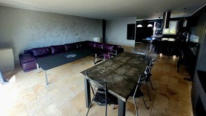 A modern living room with a sectional sofa, a dining table, and a kitchen area. - Les Oliviers du Pouget -Superb villa with heated pool & air conditioning (Le Pouget)