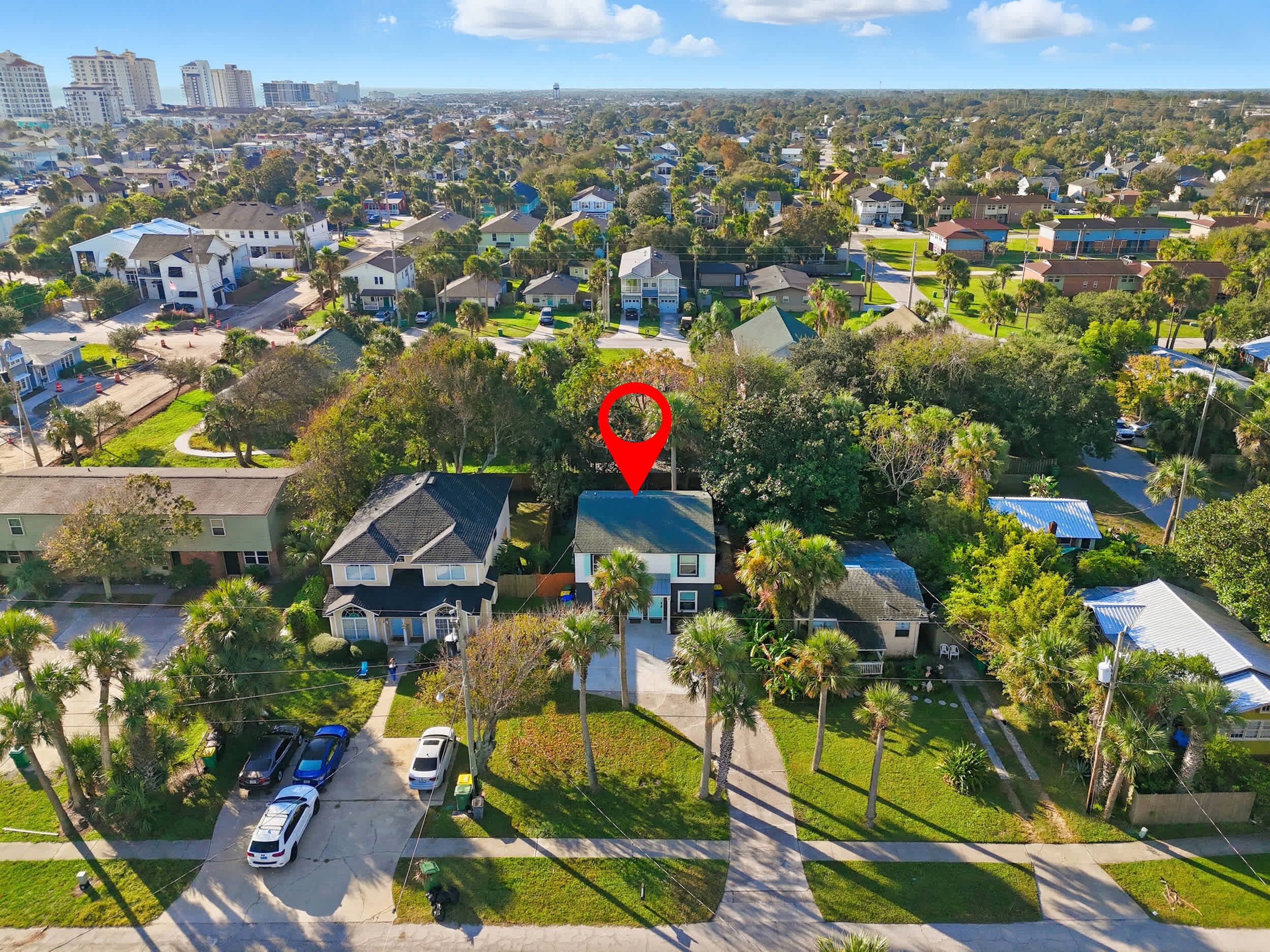 An aerial view of a residential neighborhood with houses, streets, and a prominent red location marker.