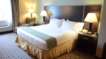Habitación de hotel con una cama grande, dos mesitas de noche con lámparas, una silla, una ventana con cortinas y una alfombra estampada.